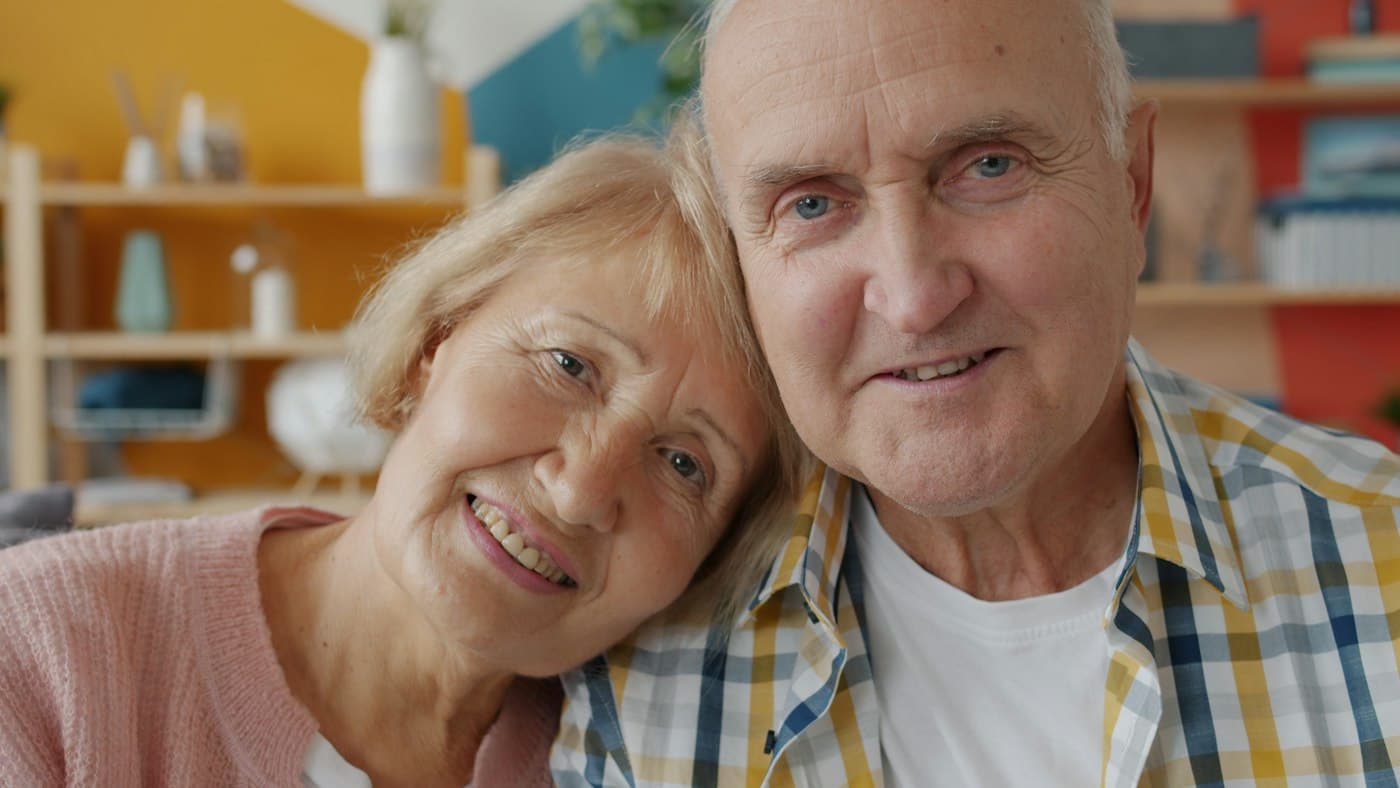 An older couple smiling with their heads together at home