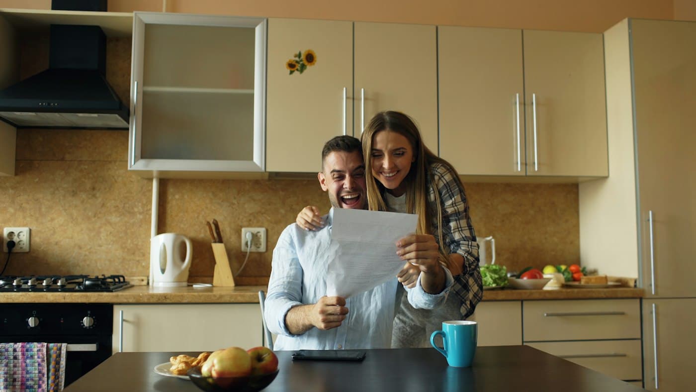 A couple reading a letter together at their kitchen table