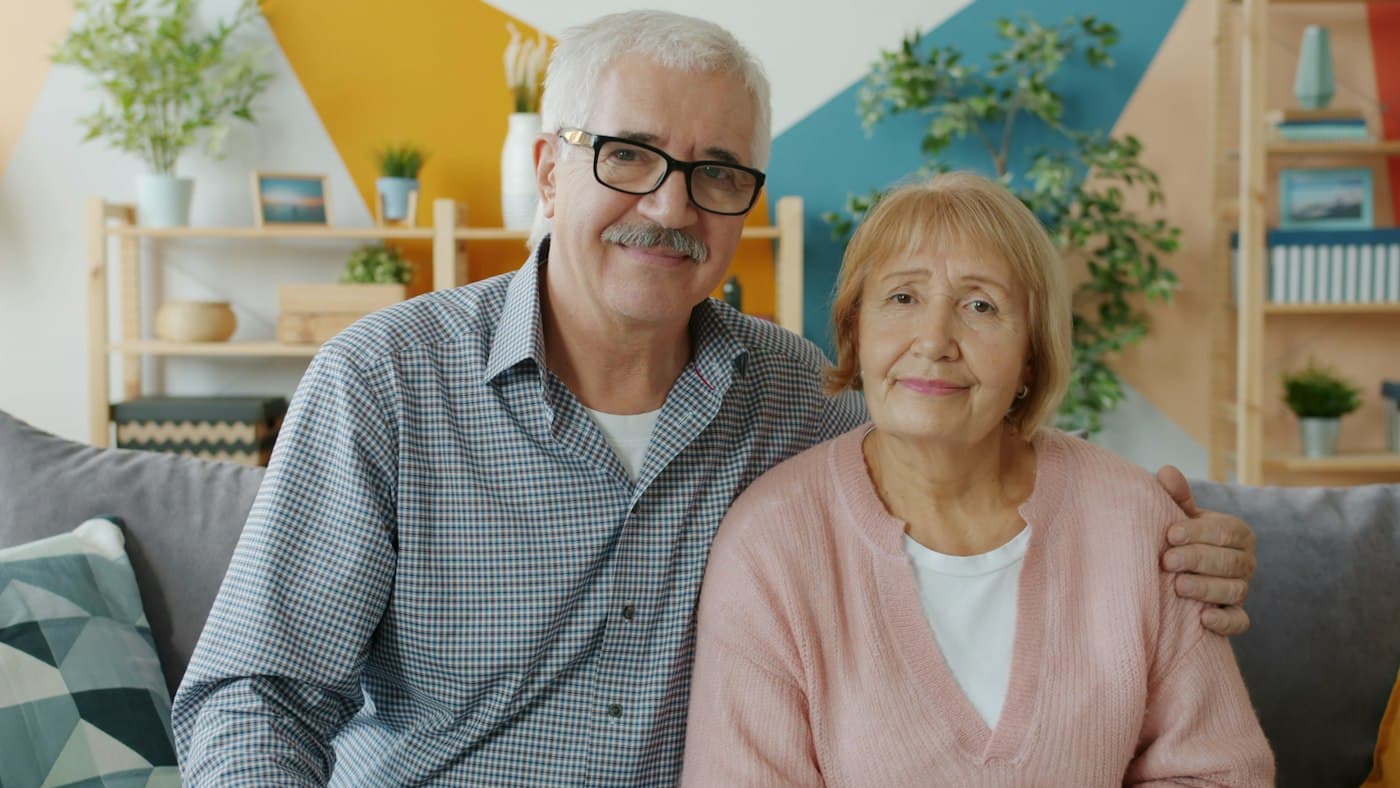 An older couple smiling together on their couch