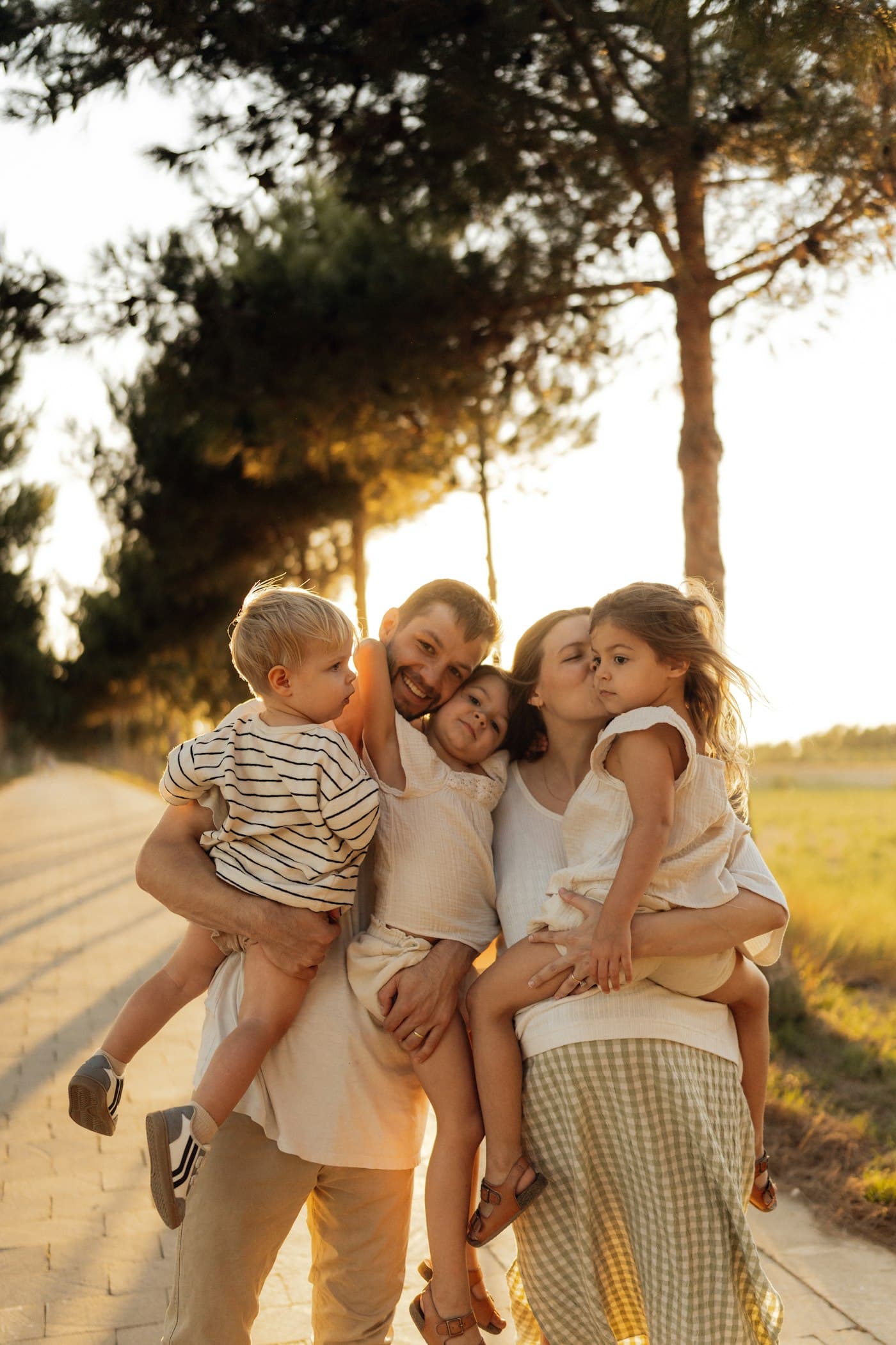 A young family hugging outdoors at golden hour
