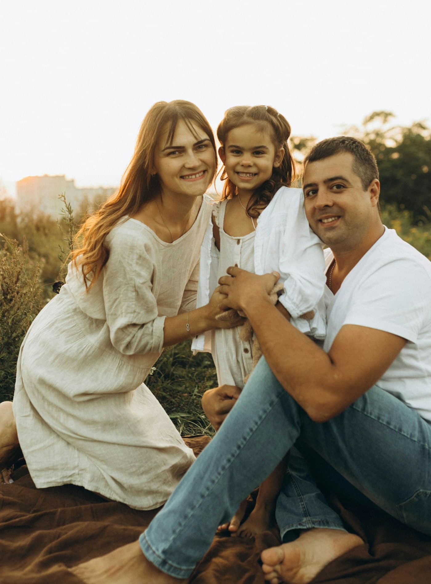 Parents with their young daughter on a blanket in a field