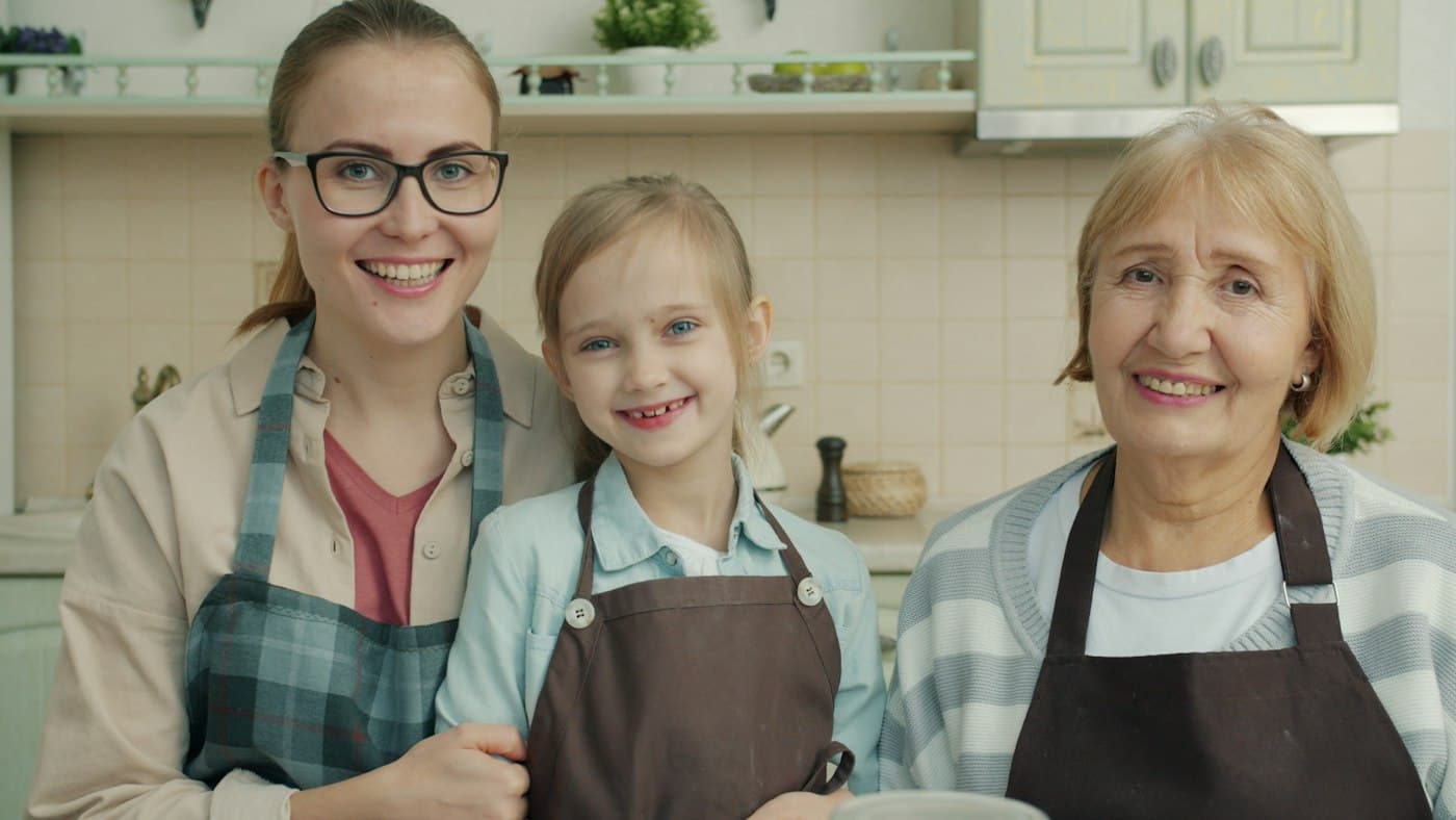 Three generations of one family smiling in the kitchen